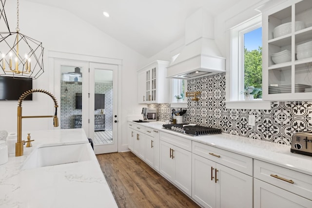 5128 Terravista Ln, Franklin, TN 37064 - kitchen with stainless steel gas stovetop, lofted ceiling, backsplash, glass insert cabinets, and custom exhaust hood