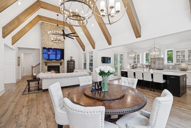5128 Terravista Ln, Franklin, TN 37064 - dining space with a chandelier, high vaulted ceiling, beam ceiling, a lit fireplace, and light wood-type flooring