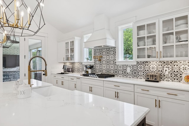 5128 Terravista Ln, Franklin, TN 37064 - kitchen featuring custom range hood, decorative backsplash, white cabinetry, stainless steel gas cooktop, and vaulted ceiling