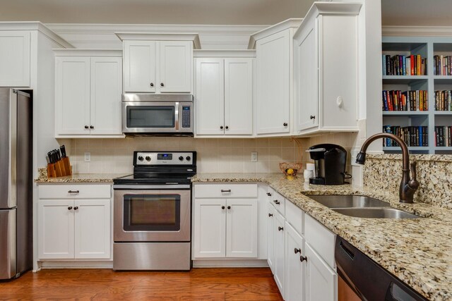 2003 Rural Plains Cir, Franklin, TN 37064 - kitchen featuring appliances with stainless steel finishes, white cabinets, light wood-style floors, and light stone counters