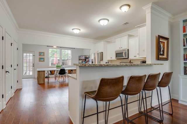 2003 Rural Plains Cir, Franklin, TN 37064 - kitchen with stainless steel appliances, ornamental molding, dark wood-style floors, a breakfast bar, and light stone countertops