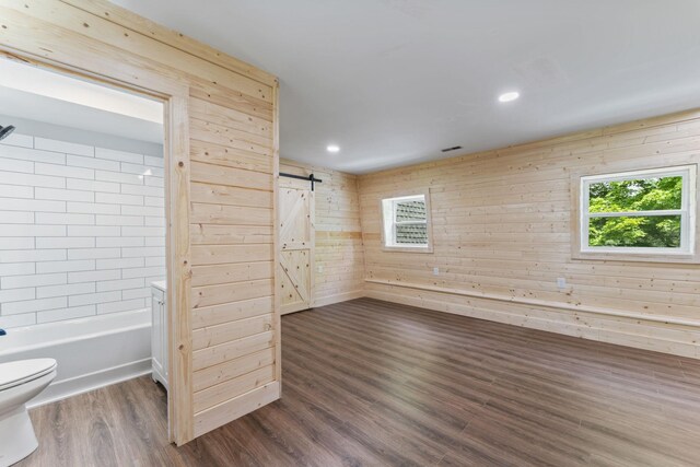 7121 Robinson Dr, Fairview, TN 37062 - basement with a barn door, dark wood-style flooring, wood walls, and recessed lighting