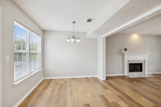 1882 Portway Rd, Spring Hill, TN 37174 - unfurnished dining area with a textured ceiling, light wood-type flooring, a chandelier, and a tiled fireplace