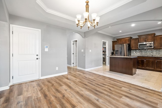 1613 Kestrel Dr, Clarksville, TN 37040 - kitchen with appliances with stainless steel finishes, arched walkways, crown molding, a chandelier, and a center island