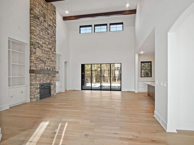 6128 Lookaway Cir, Franklin, TN 37067 - unfurnished living room with light wood finished floors, a stone fireplace, a towering ceiling, beam ceiling, and built in features