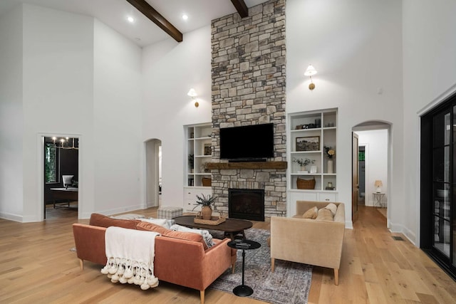6128 Lookaway Cir, Franklin, TN 37067 - living area featuring arched walkways, a high ceiling, a stone fireplace, wood finished floors, and beamed ceiling