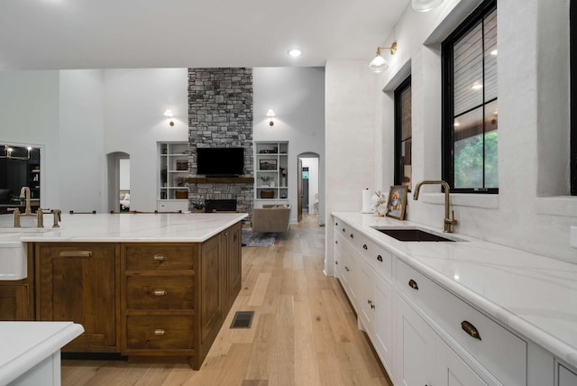 6128 Lookaway Cir, Franklin, TN 37067 - kitchen featuring arched walkways, a stone fireplace, light wood-type flooring, white cabinets, and open floor plan