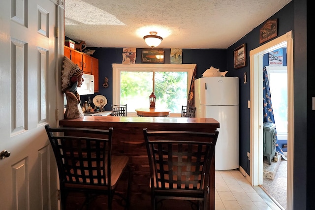 211 Lewis Cir, Dover, TN 37058 - kitchen featuring white appliances, a textured ceiling, light tile patterned floors, and brown cabinets