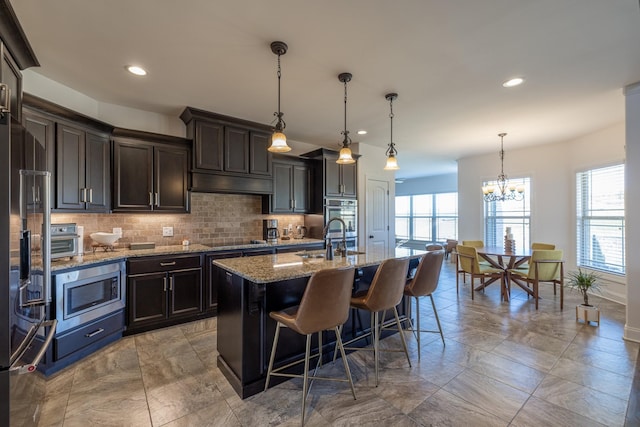160 Dobson Knob Trl, Nolensville, TN 37135 - kitchen with appliances with stainless steel finishes, tasteful backsplash, a breakfast bar area, a kitchen island with sink, and light stone counters