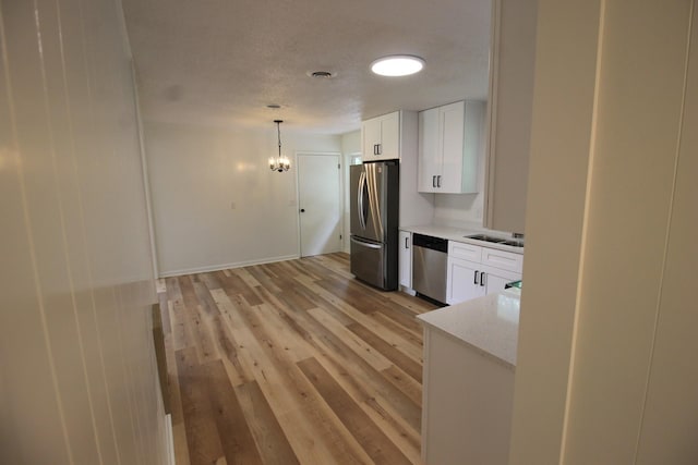 151 Dawn St, Morrison, TN 37357 - kitchen with stainless steel appliances, a chandelier, white cabinetry, hanging light fixtures, and light wood-style flooring