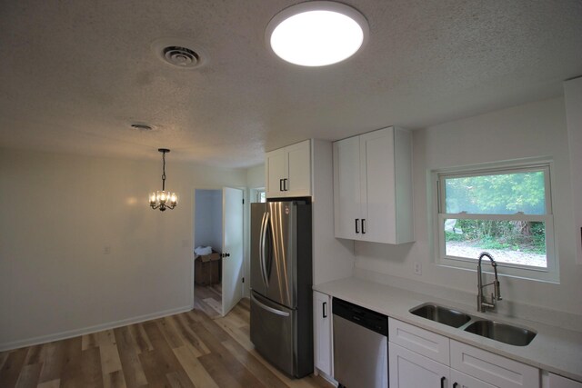 151 Dawn St, Morrison, TN 37357 - kitchen with appliances with stainless steel finishes, a textured ceiling, white cabinets, light wood-type flooring, and a chandelier