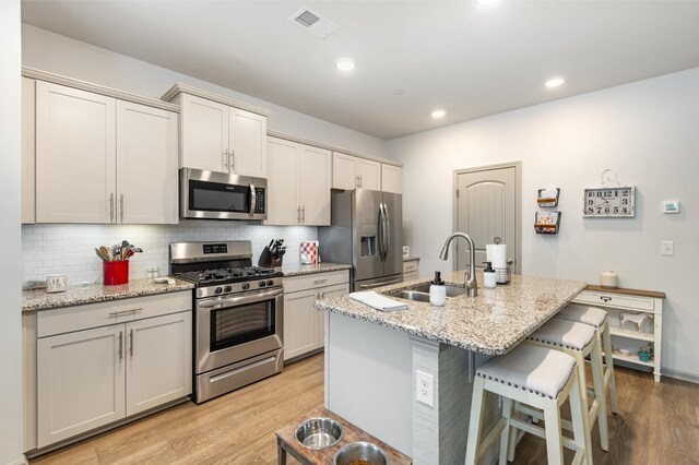 414 Manor Row, Pleasant View, TN 37146 - kitchen with appliances with stainless steel finishes, light wood-style flooring, a breakfast bar area, decorative backsplash, and recessed lighting