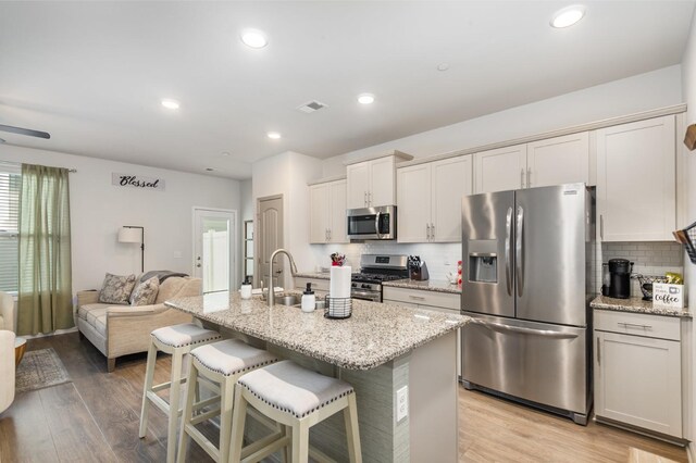 414 Manor Row, Pleasant View, TN 37146 - kitchen featuring stainless steel appliances, a breakfast bar area, decorative backsplash, light wood-type flooring, and recessed lighting