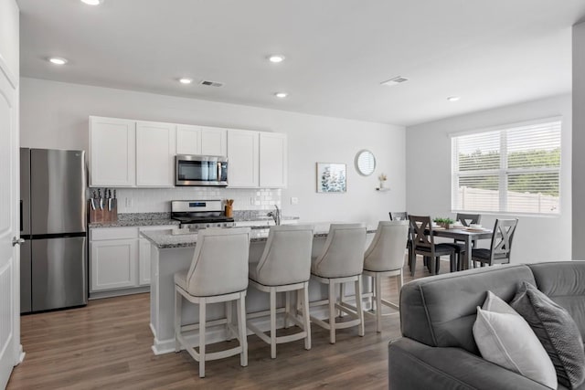 2400 Kaycee Ct, Lebanon, TN 37087 - kitchen with appliances with stainless steel finishes, tasteful backsplash, a breakfast bar area, wood finished floors, and white cabinetry