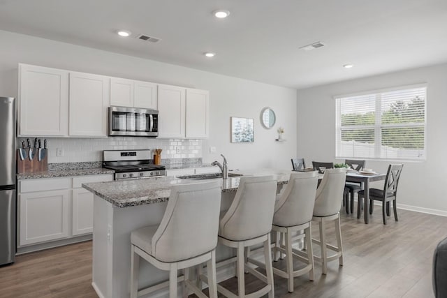 2400 Kaycee Ct, Lebanon, TN 37087 - kitchen with stainless steel appliances, tasteful backsplash, a kitchen breakfast bar, light stone counters, and light wood-style floors