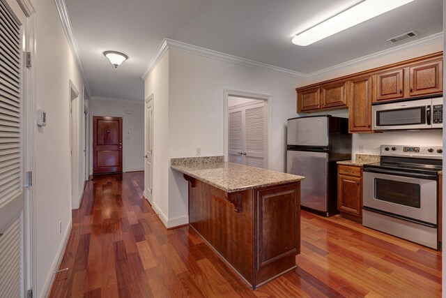 301 Criddle St Unit 304, Nashville, TN 37219 - kitchen featuring appliances with stainless steel finishes, wood finished floors, brown cabinets, light stone countertops, and a peninsula