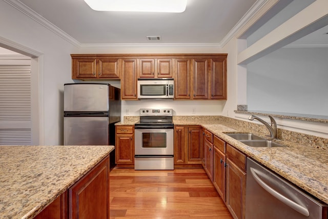 301 Criddle St Unit 304, Nashville, TN 37219 - kitchen with appliances with stainless steel finishes, crown molding, light stone counters, light wood-style flooring, and brown cabinetry