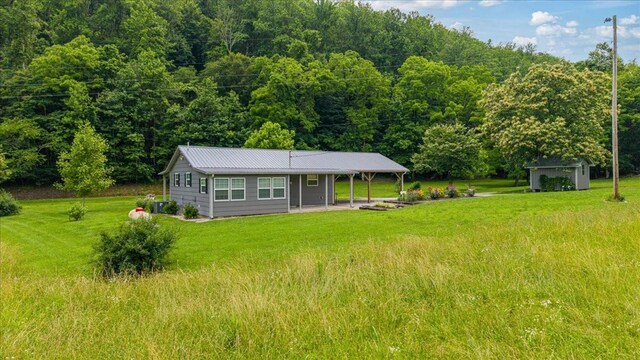 49 Je Sartain Rd, Manchester, TN 37355 - rear view of house featuring a forest view, a lawn, a metal roof, and an outdoor structure
