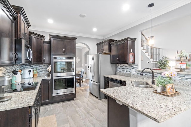 1148 Folly Beach Dr, Clarksville, TN 37042 - kitchen with appliances with stainless steel finishes, dark brown cabinets, a peninsula, arched walkways, and tasteful backsplash