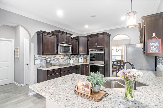 1148 Folly Beach Dr, Clarksville, TN 37042 - kitchen featuring appliances with stainless steel finishes, arched walkways, dark brown cabinetry, decorative backsplash, and decorative light fixtures