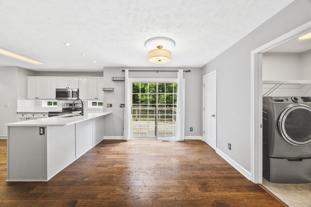 2135 Loudenslager Dr, Thompsons Station, TN 37179 - kitchen with stainless steel appliances, a peninsula, dark wood finished floors, washer / clothes dryer, and white cabinets