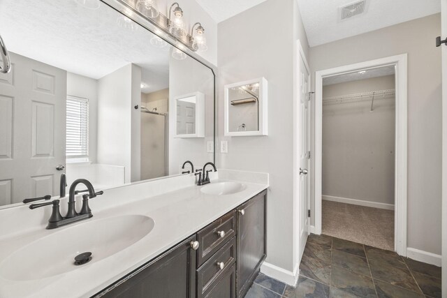2135 Loudenslager Dr, Thompsons Station, TN 37179 - bathroom with a stall shower, a walk in closet, double vanity, stone finish floors, and a textured ceiling