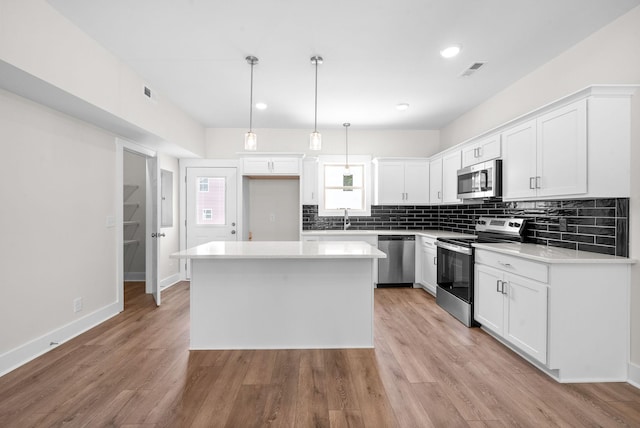 109 Adkins St Unit A, Clarksville, TN 37042 - kitchen with appliances with stainless steel finishes, a center island, tasteful backsplash, white cabinetry, and decorative light fixtures
