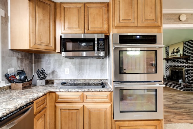 3037 Tunnel Rd, Westmoreland, TN 37186 - kitchen featuring appliances with stainless steel finishes, wood finished floors, decorative backsplash, light stone counters, and a fireplace