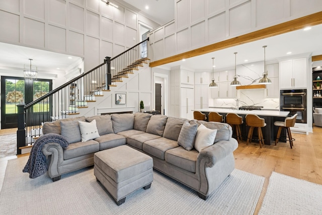 1485 Harrison Rd, Murfreesboro, TN 37128 - living room featuring a decorative wall, a high ceiling, stairway, light wood-style flooring, and a chandelier