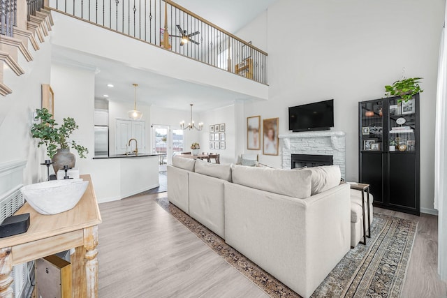 134 Chisum Ct, Clarksville, TN 37043 - living area with wood finished floors, a fireplace, a chandelier, a high ceiling, and ceiling fan