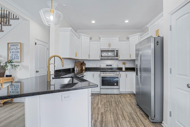 134 Chisum Ct, Clarksville, TN 37043 - kitchen with stainless steel appliances, a peninsula, white cabinetry, light wood-style floors, and crown molding