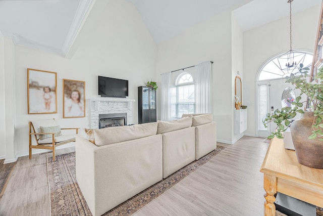 134 Chisum Ct, Clarksville, TN 37043 - living room featuring a fireplace, high vaulted ceiling, light wood-style floors, a chandelier, and ornamental molding