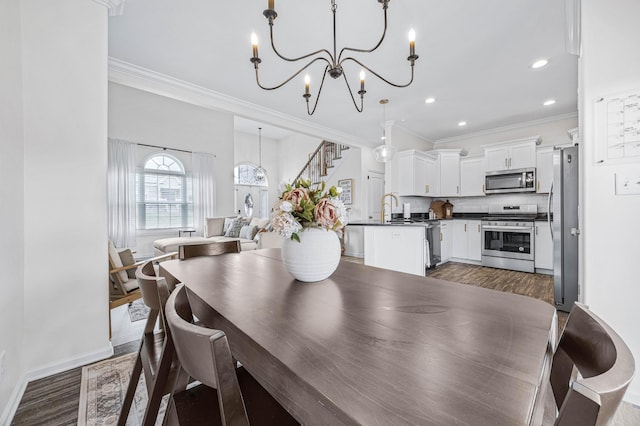 134 Chisum Ct, Clarksville, TN 37043 - dining space with a chandelier, dark wood finished floors, ornamental molding, recessed lighting, and stairs