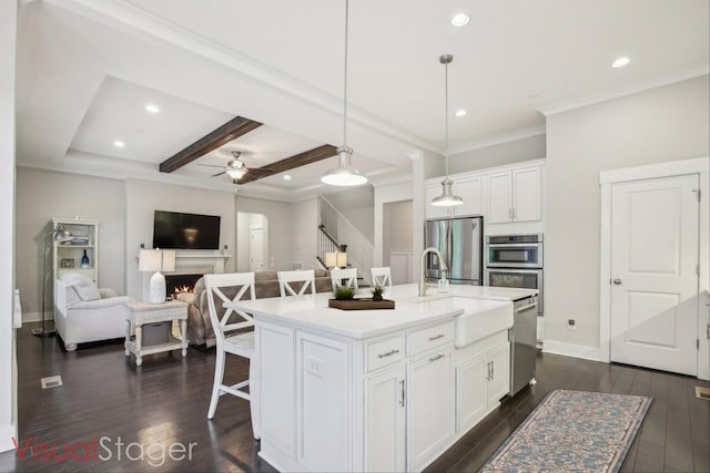 2016 Oliver Dr, Mount Juliet, TN 37122 - kitchen featuring appliances with stainless steel finishes, ceiling fan, beamed ceiling, white cabinets, and a lit fireplace