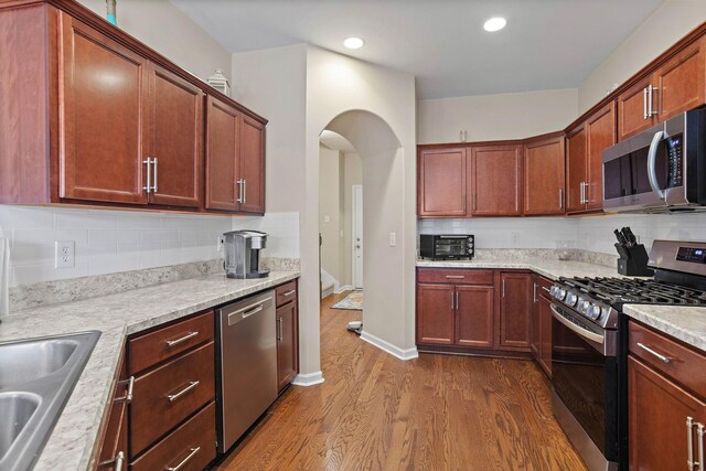 341 Lola Ln, Cottontown, TN 37048 - kitchen featuring stainless steel appliances, dark wood finished floors, tasteful backsplash, arched walkways, and recessed lighting