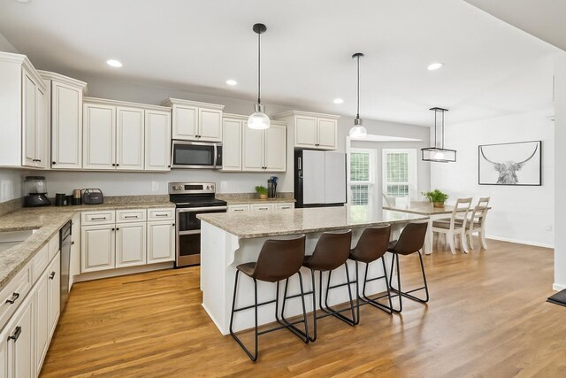 1005 Rudder Dr, Spring Hill, TN 37174 - kitchen with stainless steel appliances, a breakfast bar, a kitchen island, light wood-style flooring, and recessed lighting