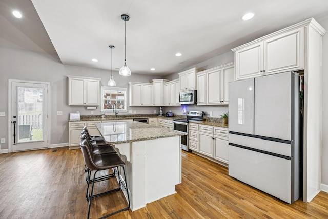 1005 Rudder Dr, Spring Hill, TN 37174 - kitchen featuring stainless steel appliances, a center island, light wood-style flooring, decorative light fixtures, and white cabinets