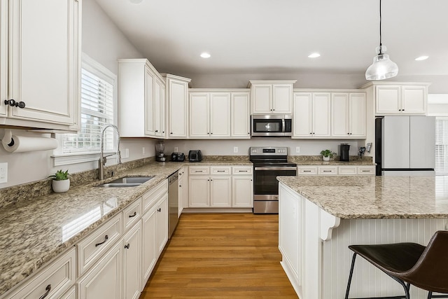 1005 Rudder Dr, Spring Hill, TN 37174 - kitchen featuring appliances with stainless steel finishes, light wood-type flooring, white cabinets, a breakfast bar, and recessed lighting