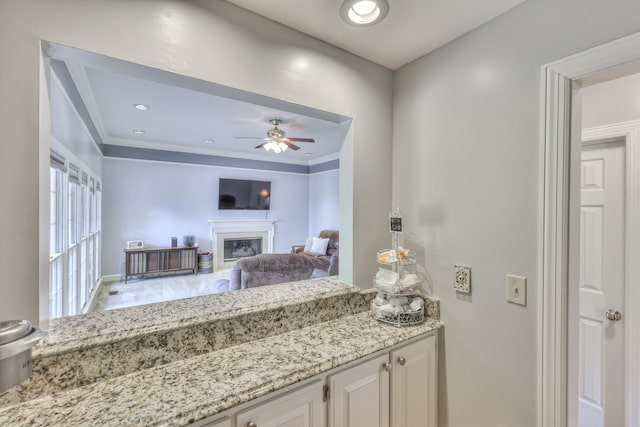101 Spring Creek Trl, Hendersonville, TN 37075 - kitchen featuring ceiling fan, a glass covered fireplace, light stone counters, crown molding, and white cabinetry