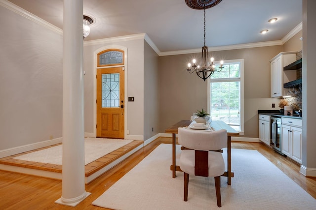 101 Oak Dr, Waverly, TN 37185 - dining room featuring beverage cooler, light wood-style flooring, a chandelier, crown molding, and decorative columns