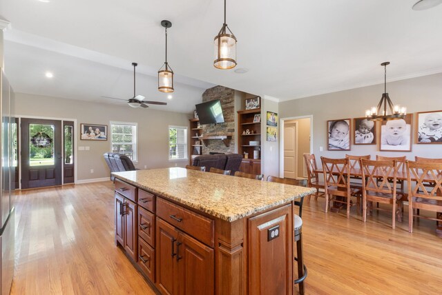 3215 Church St, Burns, TN 37029 - kitchen featuring light wood finished floors, ceiling fan, a center island, a stone fireplace, and decorative light fixtures