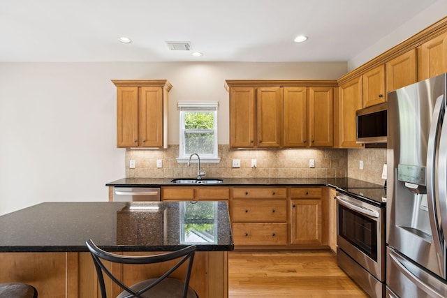 2025 Morrison Ave, Spring Hill, TN 37174 - kitchen featuring appliances with stainless steel finishes, light wood-style flooring, a breakfast bar area, tasteful backsplash, and dark stone countertops