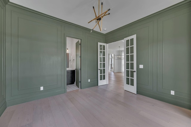 6060 Pasquo Rd, Nashville, TN 37221 - unfurnished room with a chandelier, french doors, a decorative wall, and wood finished floors
