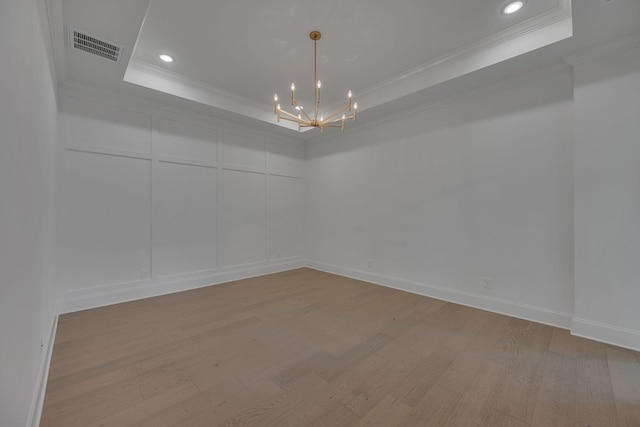 6060 Pasquo Rd, Nashville, TN 37221 - empty room with a raised ceiling, ornamental molding, a chandelier, a decorative wall, and light wood-type flooring
