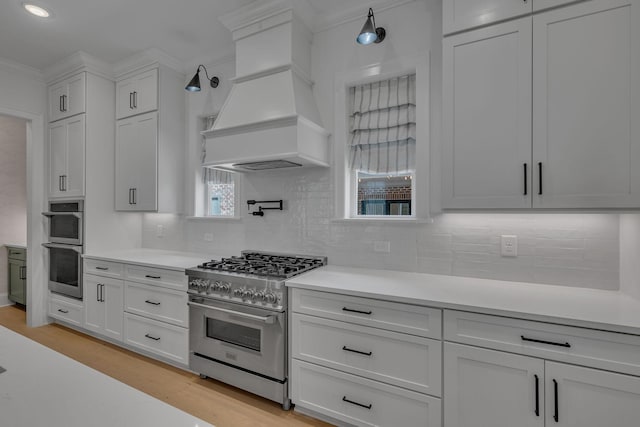 6060 Pasquo Rd, Nashville, TN 37221 - kitchen with appliances with stainless steel finishes, custom exhaust hood, light countertops, white cabinetry, and light wood-style flooring