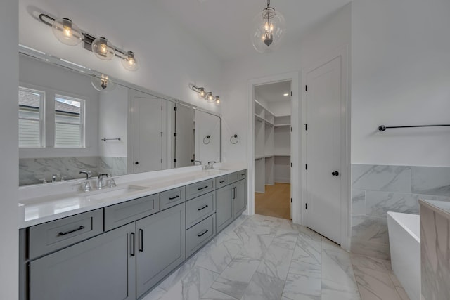 6060 Pasquo Rd, Nashville, TN 37221 - bathroom with double vanity, a freestanding bath, a walk in closet, marble finish floors, and tile walls