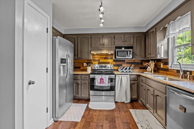 5455 Bales Rd, Cunningham, TN 37052 - kitchen with appliances with stainless steel finishes, under cabinet range hood, dark wood-type flooring, decorative backsplash, and light stone countertops