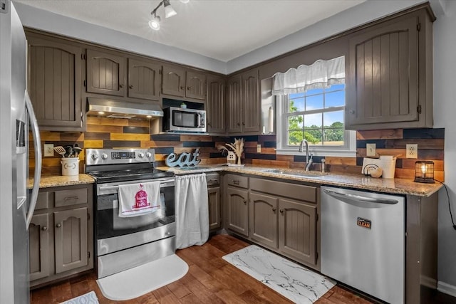 5455 Bales Rd, Cunningham, TN 37052 - kitchen with appliances with stainless steel finishes, under cabinet range hood, dark wood-style flooring, light stone countertops, and backsplash