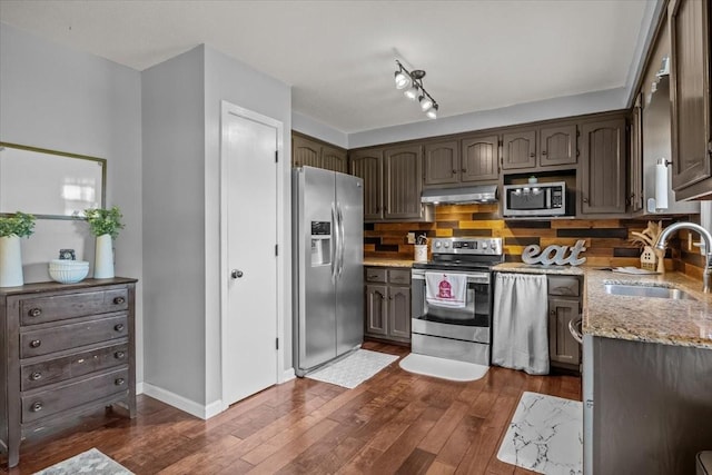 5455 Bales Rd, Cunningham, TN 37052 - kitchen with appliances with stainless steel finishes, under cabinet range hood, dark wood-style flooring, decorative backsplash, and light stone countertops