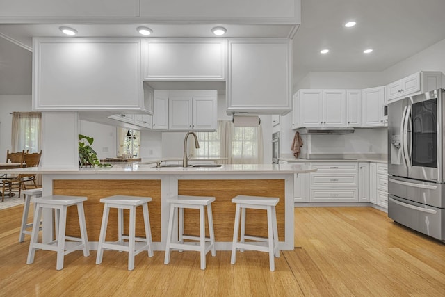 1697 Curtis Chapel Rd, Mc Ewen, TN 37101 - kitchen featuring appliances with stainless steel finishes, light countertops, light wood-style floors, a kitchen breakfast bar, and recessed lighting